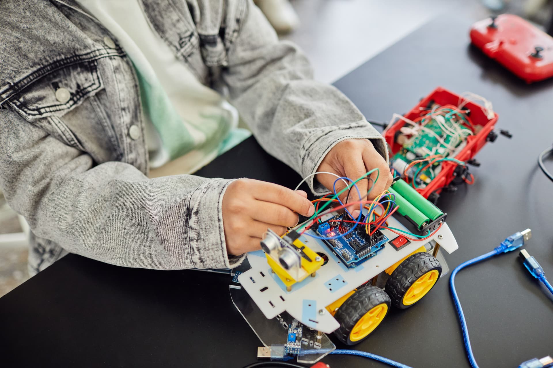 A student wiring a small robotics car during a STEAM class