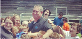 Jeff surrounded by a crowd of laughing kids at an outdoor event
