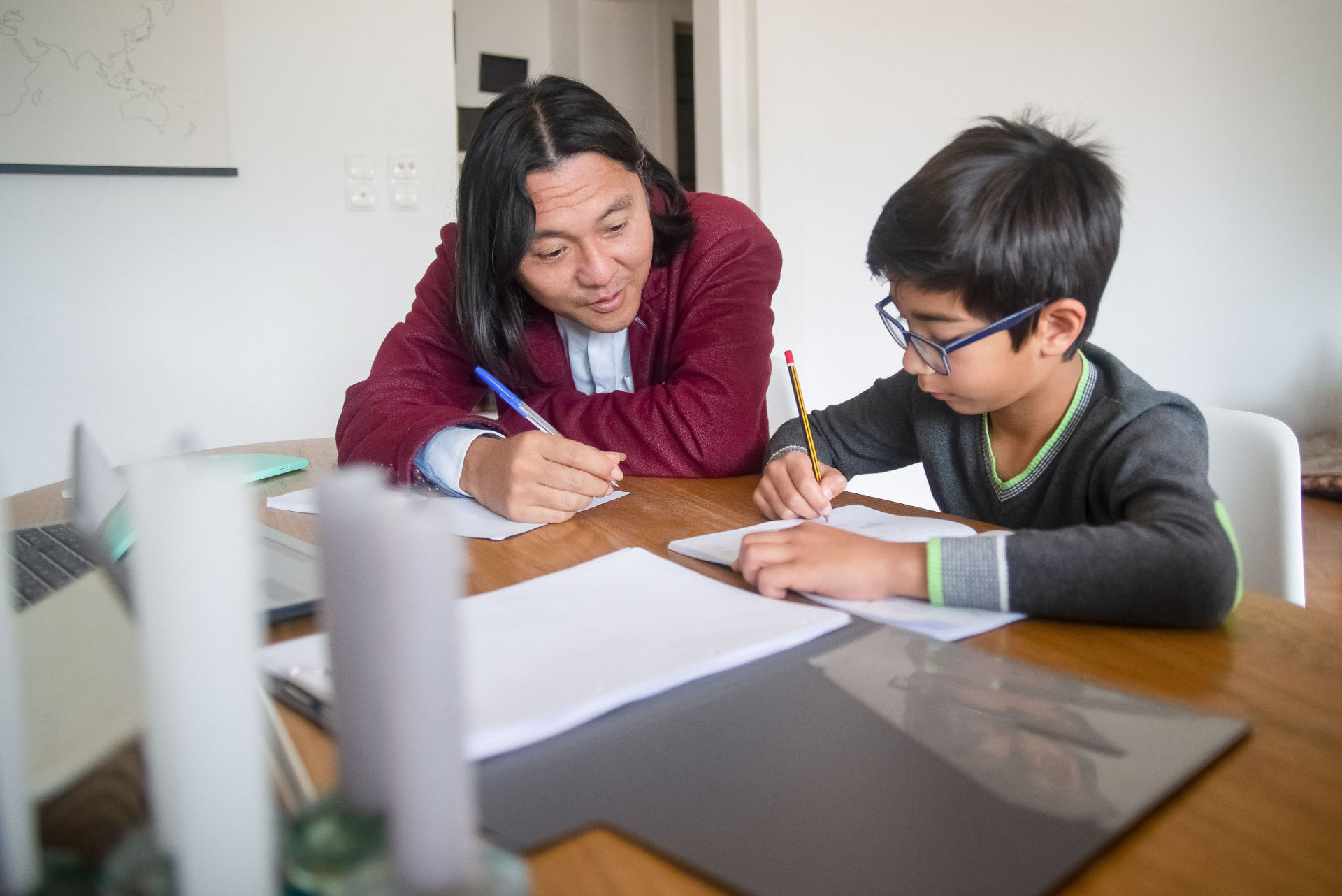 A father working through a lesson at the table with his son