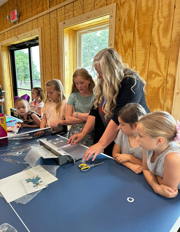 Paula helping a group of girls with a laminating project at the co-op